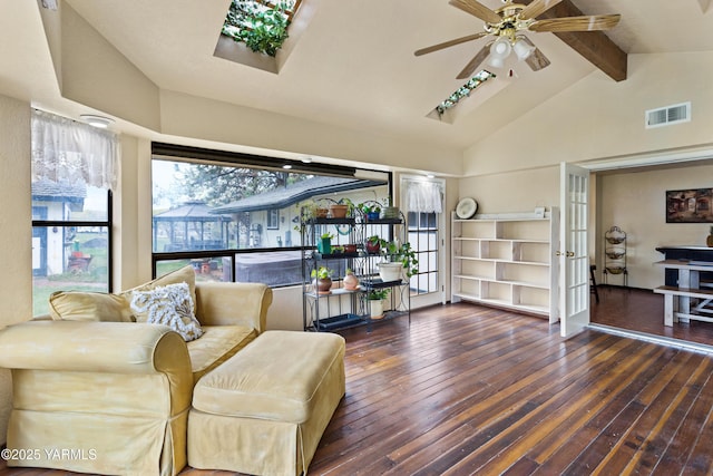 sitting room featuring vaulted ceiling with skylight, visible vents, dark wood finished floors, and ceiling fan