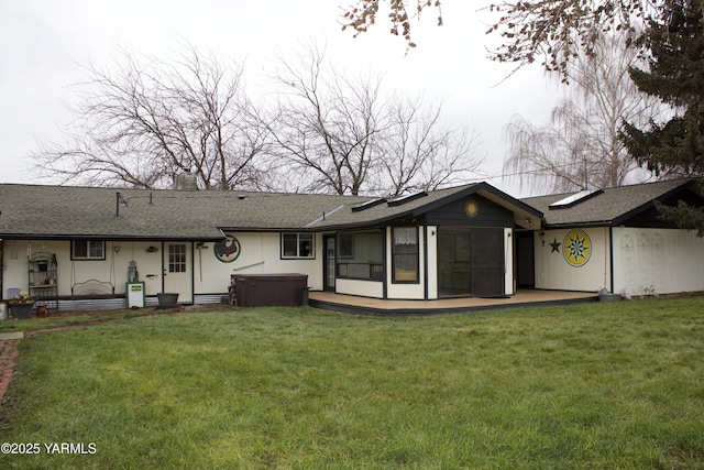 back of property featuring a chimney, roof with shingles, a yard, and a hot tub