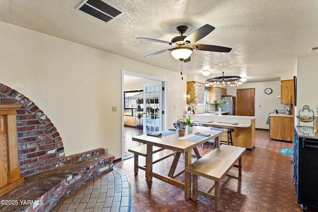 dining room with ceiling fan, a textured ceiling, and visible vents