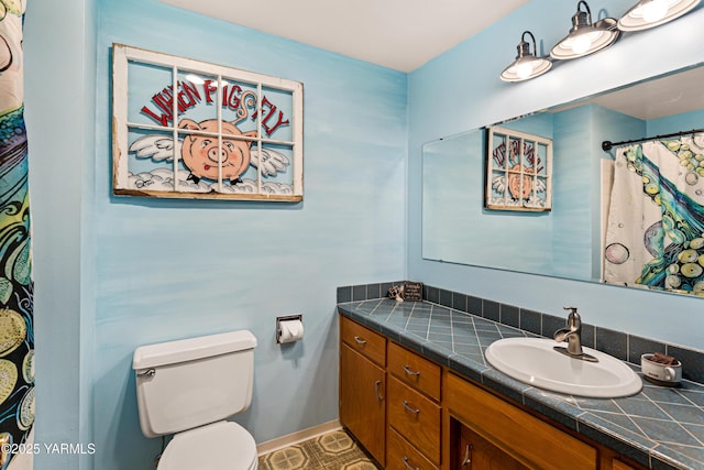 bathroom with baseboards, vanity, and toilet