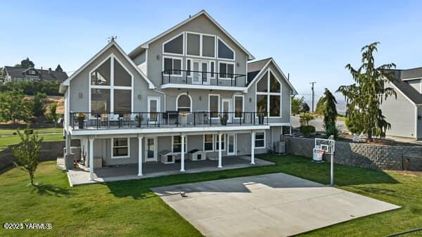 back of property with a patio, a balcony, and a lawn