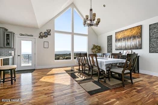 921 Tibbling Rd, Selah, WA 98942 - dining room featuring a chandelier, high vaulted ceiling, baseboards, and dark wood finished floors