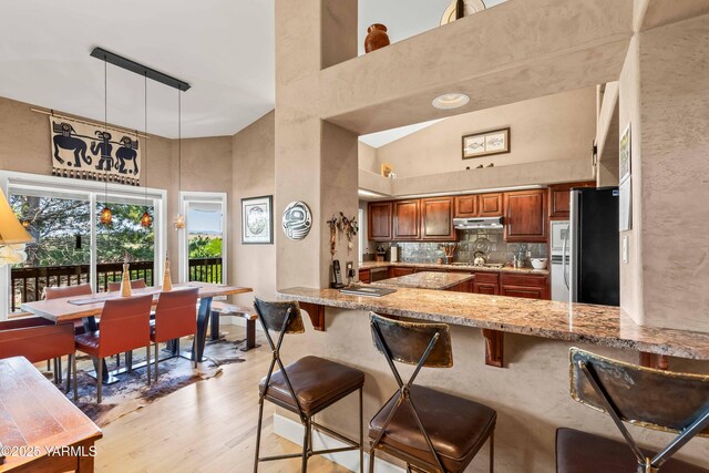 131 Katie Ln, Selah, WA 98942 - kitchen featuring stainless steel appliances, a towering ceiling, light wood-type flooring, brown cabinetry, and under cabinet range hood