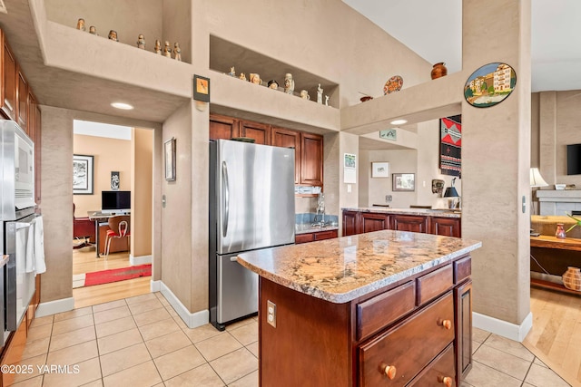 131 Katie Ln, Selah, WA 98942 - kitchen featuring freestanding refrigerator, light tile patterned floors, baseboards, a towering ceiling, and light stone countertops
