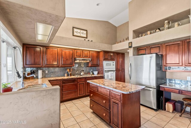 131 Katie Ln, Selah, WA 98942 - kitchen with stainless steel appliances, under cabinet range hood, light tile patterned floors, tasteful backsplash, and light stone countertops