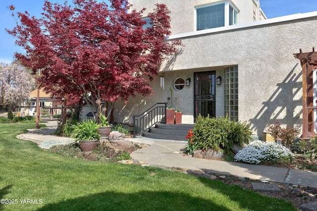 property entrance featuring a lawn and stucco siding