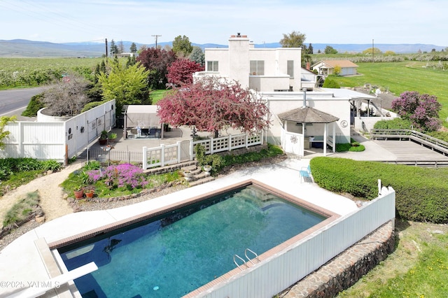 rear view of property featuring a mountain view, a patio, fence private yard, and an outdoor pool
