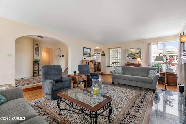 living room with baseboards, arched walkways, and light wood-style flooring