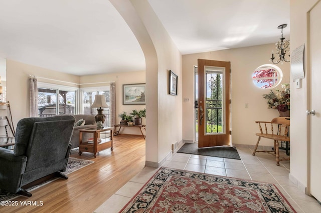foyer featuring visible vents, light tile patterned flooring, baseboards, arched walkways, and a notable chandelier