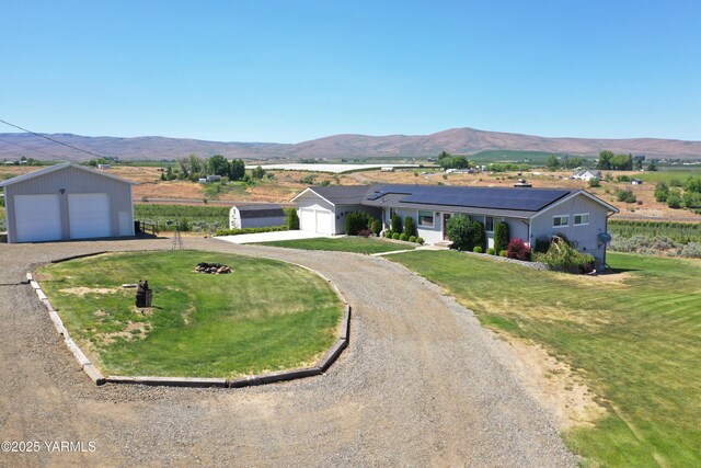 15911 Fisk Rd, Yakima, WA 98908 - view of front of home with a front lawn, roof mounted solar panels, a mountain view, a garage, and an outdoor structure