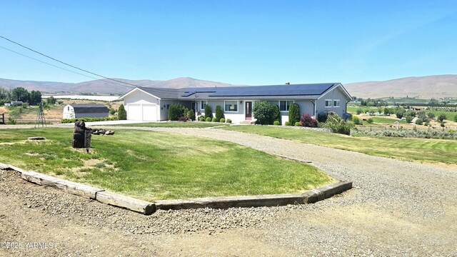 15911 Fisk Rd, Yakima, WA 98908 - ranch-style home with roof mounted solar panels, an attached garage, a mountain view, a front lawn, and driveway
