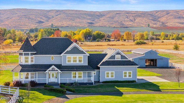 view of front of house with covered porch, a front lawn, and a mountain view