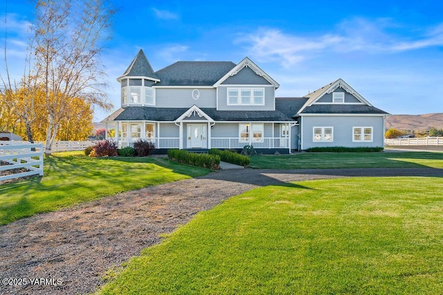 view of front of house featuring covered porch, fence, and a front lawn