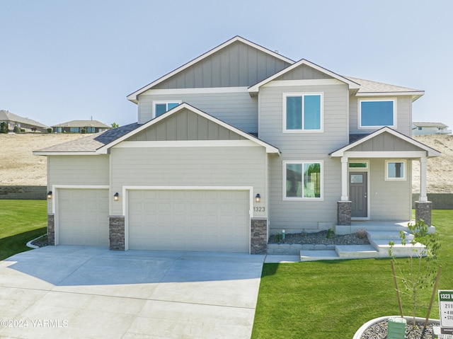 craftsman-style home featuring a shingled roof, board and batten siding, a front yard, a garage, and driveway