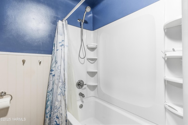 bathroom featuring shower / bath combo and a wainscoted wall