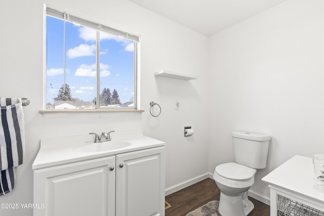half bathroom featuring baseboards, wood finished floors, toilet, and vanity