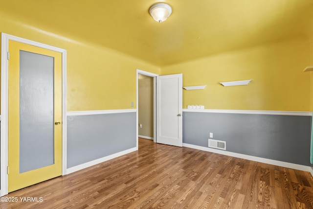 spare room featuring baseboards, wood finished floors, and visible vents