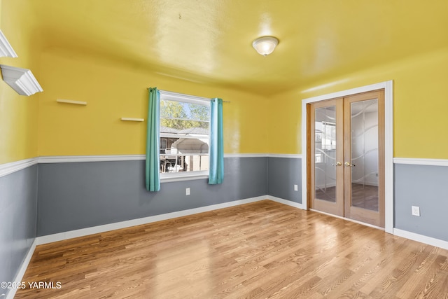 unfurnished room featuring wood finished floors, baseboards, and french doors