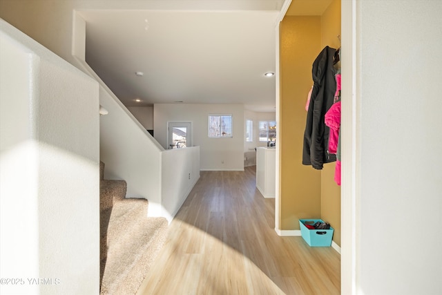 hall with light wood-type flooring, stairway, and baseboards