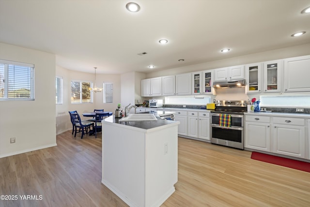 kitchen featuring range with two ovens, dark countertops, white cabinetry, and a sink