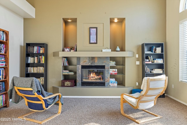 living area featuring carpet floors, baseboards, and a tiled fireplace