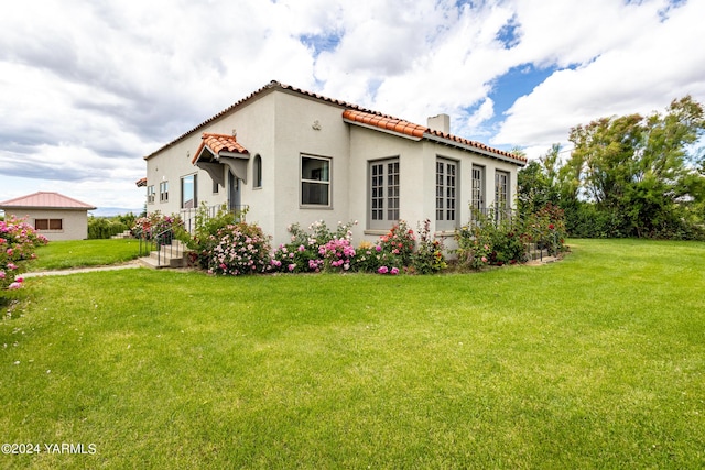 view of side of property with a tile roof, a yard, and stucco siding