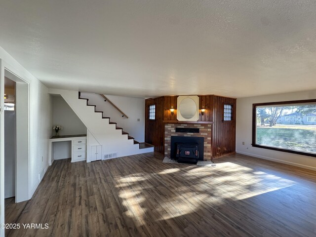 3803 Tieton Dr, Yakima, WA 98902 - unfurnished living room featuring wood finished floors, a brick fireplace, stairs, baseboards, and a textured ceiling
