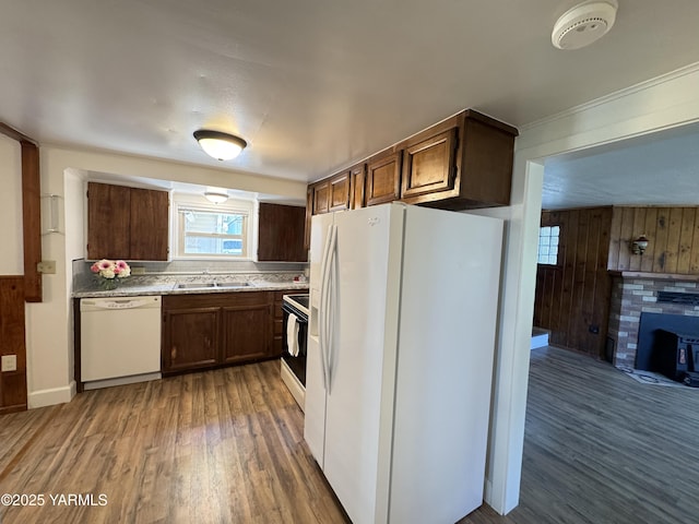3803 Tieton Dr, Yakima, WA 98902 - kitchen with white appliances, a sink, wood finished floors, wood walls, and a fireplace