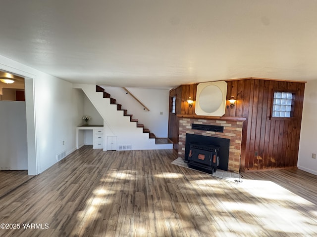 3803 Tieton Dr, Yakima, WA 98902 - unfurnished living room with wood finished floors, stairs, baseboards, a wood stove, and wood walls