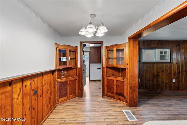 3803 Tieton Dr, Yakima, WA 98902 - hallway featuring wooden walls, a chandelier, light wood-type flooring, crown molding, and plenty of natural light
