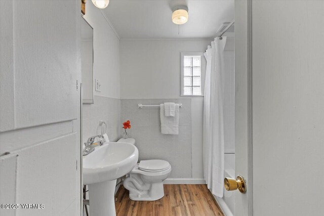 3803 Tieton Dr, Yakima, WA 98902 - bathroom featuring toilet, wood finished floors, shower / tub combo with curtain, ornamental molding, and tile walls