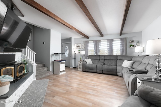 living room featuring light wood-style floors, beam ceiling, and stairs