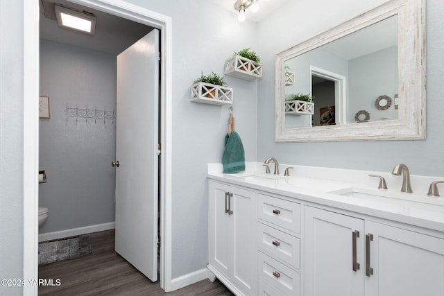 bathroom with double vanity, wood finished floors, a sink, and toilet