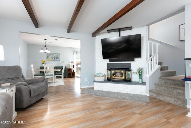 living area with light wood-type flooring, baseboards, stairway, and beamed ceiling