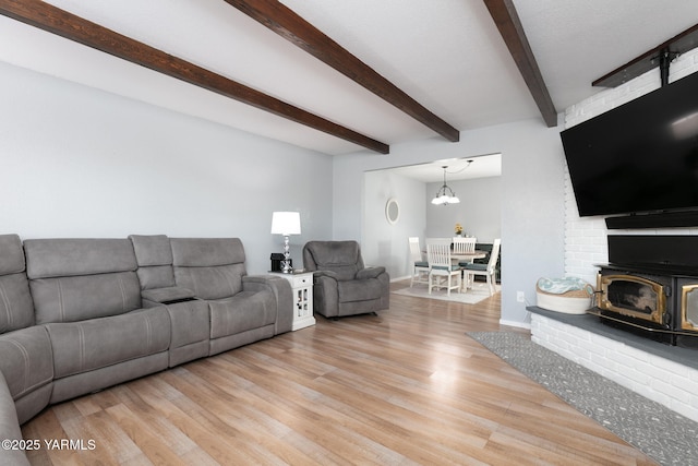 living area featuring baseboards, beamed ceiling, and light wood finished floors