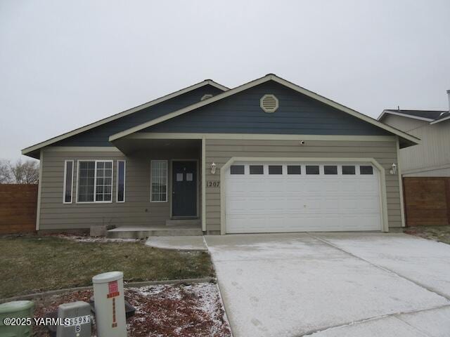 ranch-style house featuring an attached garage, driveway, and fence