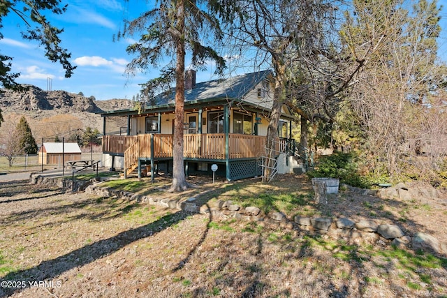 back of property with a deck with mountain view and stairs