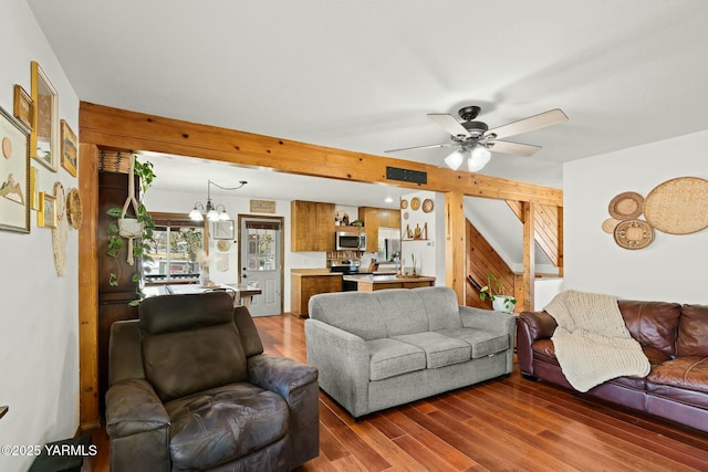 living area with dark wood finished floors and ceiling fan with notable chandelier