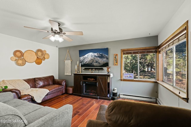 living room with baseboard heating, a fireplace, a ceiling fan, and dark wood-style flooring