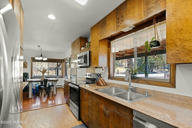 kitchen featuring an inviting chandelier, a sink, stainless steel appliances, light countertops, and light wood-style floors