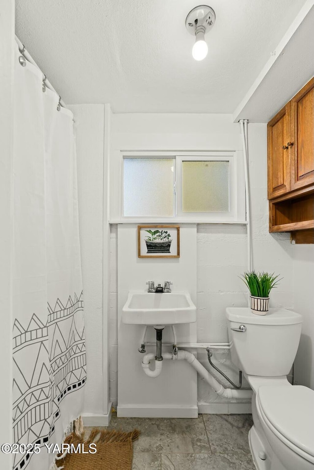 bathroom with curtained shower, baseboards, toilet, a textured ceiling, and a sink