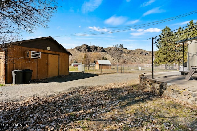 view of yard featuring a mountain view, a storage shed, an outdoor structure, and fence