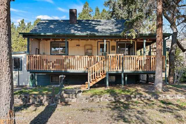 back of property featuring stairs, roof with shingles, and a chimney