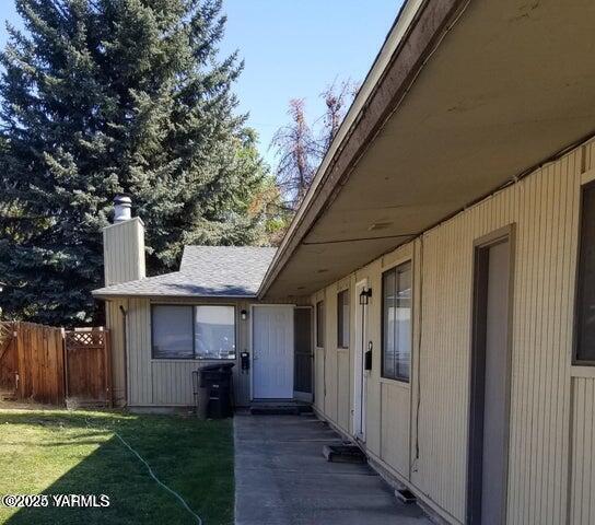 view of property exterior with a yard, a chimney, and fence