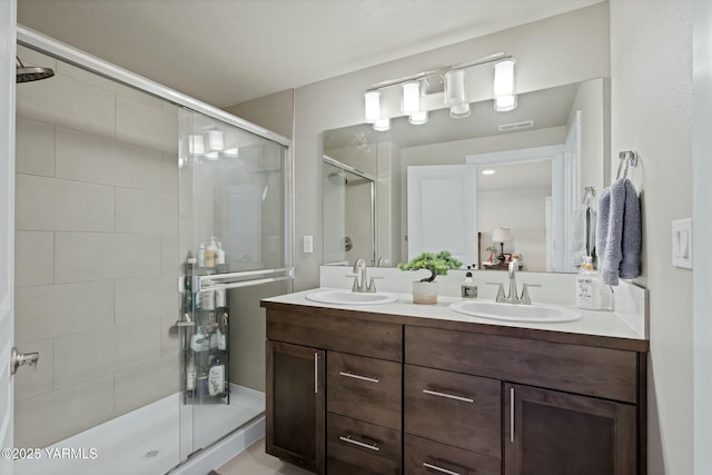 full bathroom with double vanity, a sink, visible vents, and a shower stall