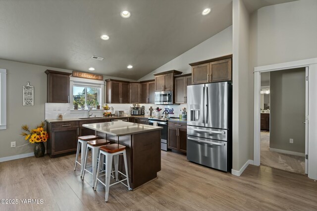 kitchen featuring light wood finished floors, visible vents, a center island, stainless steel appliances, and a kitchen bar