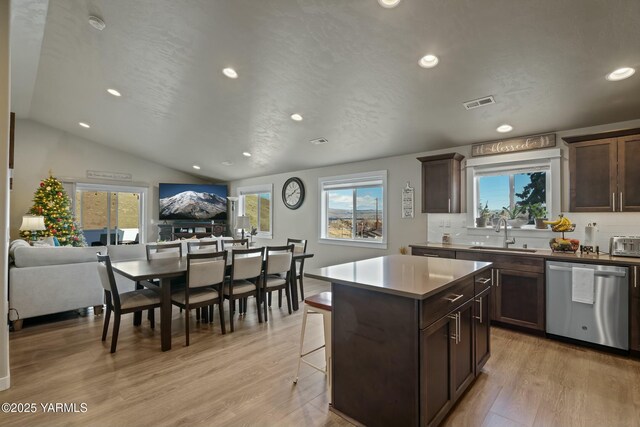 kitchen with light wood-style floors, open floor plan, a kitchen island, a sink, and dishwasher