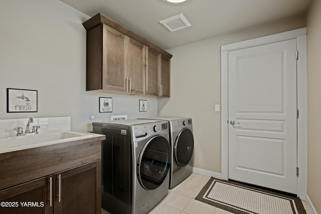 laundry room with light tile patterned floors, separate washer and dryer, a sink, visible vents, and cabinet space