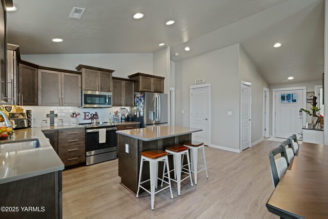 kitchen with a center island, stainless steel appliances, lofted ceiling, light countertops, and a sink