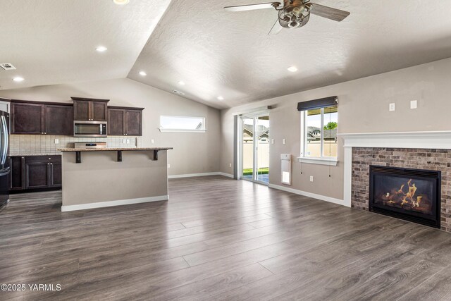 2201 S 62nd Ave, Yakima, WA 98903 - unfurnished living room with lofted ceiling, ceiling fan, dark wood-style flooring, a fireplace, and a textured ceiling